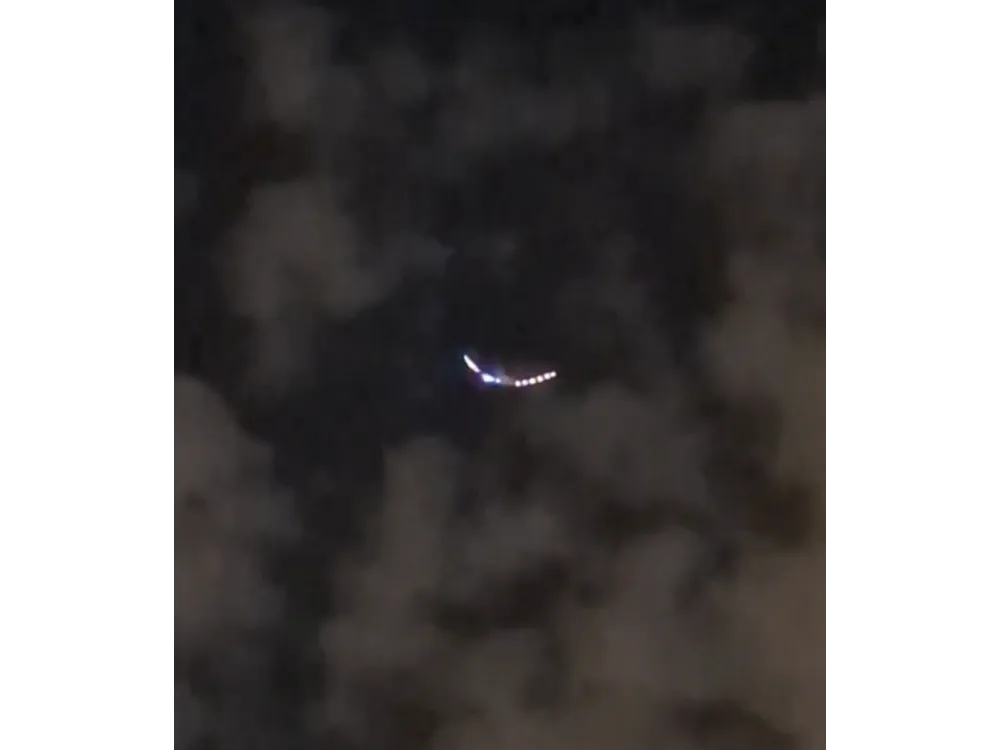 A bright crescent-shaped light seen through broken dark cloud.