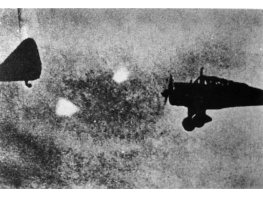 Wartime photograph of a bomber with several bright round lights keeping pace alongside it.