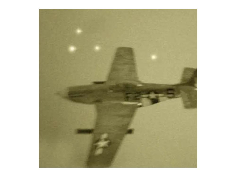 Sepia wartime photograph of a P-51 Mustang with three bright orbs above and beside it.